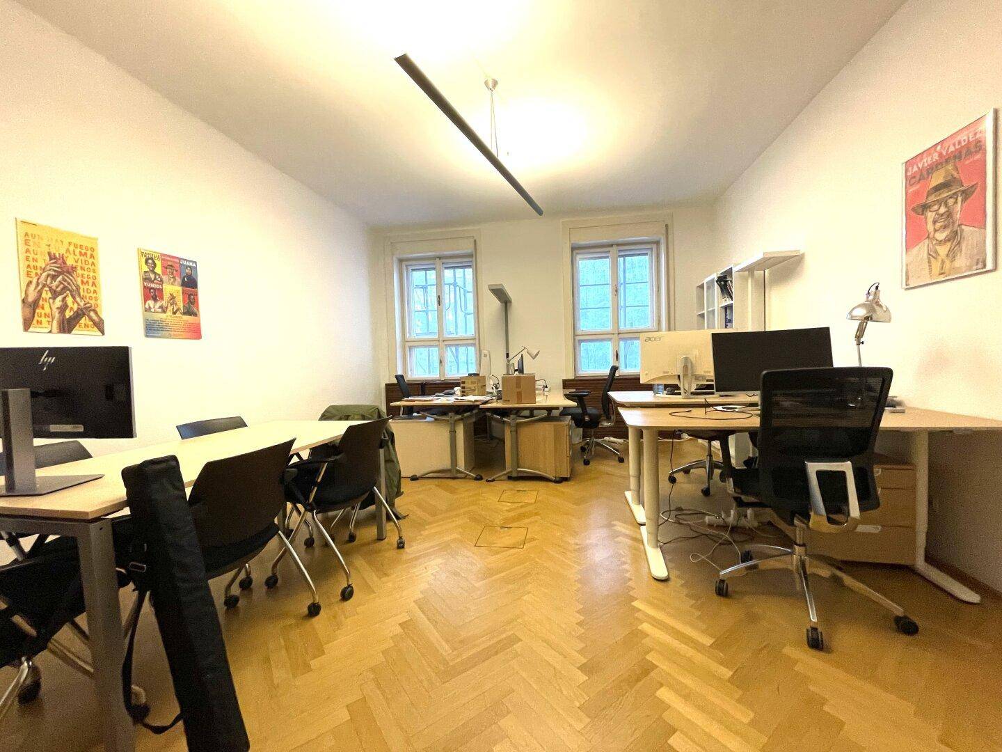 Großes Büro mit mehreren Schreibtischen, ergonomischen Stühlen und Fischgrätparkettboden.