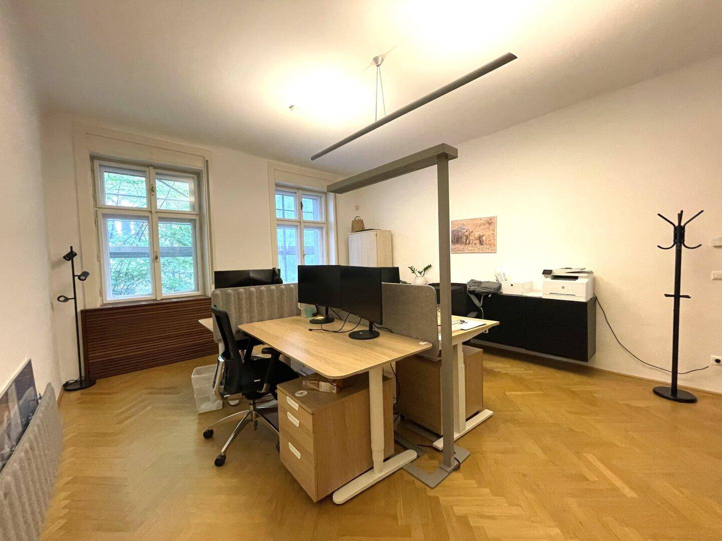Helles Büro mit zwei Arbeitsplätzen, großen Fenstern und klassischem Fischgrätparkett.