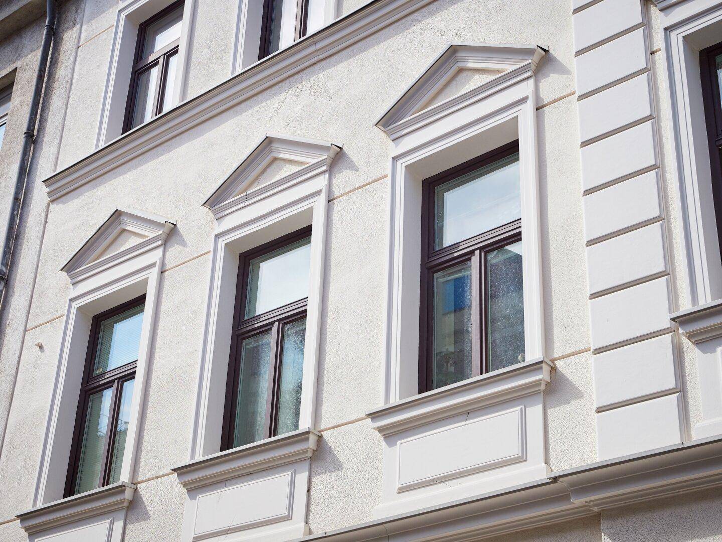 Detailansicht der eleganten Fassade eines Altbaus mit verzierten Fenstern.