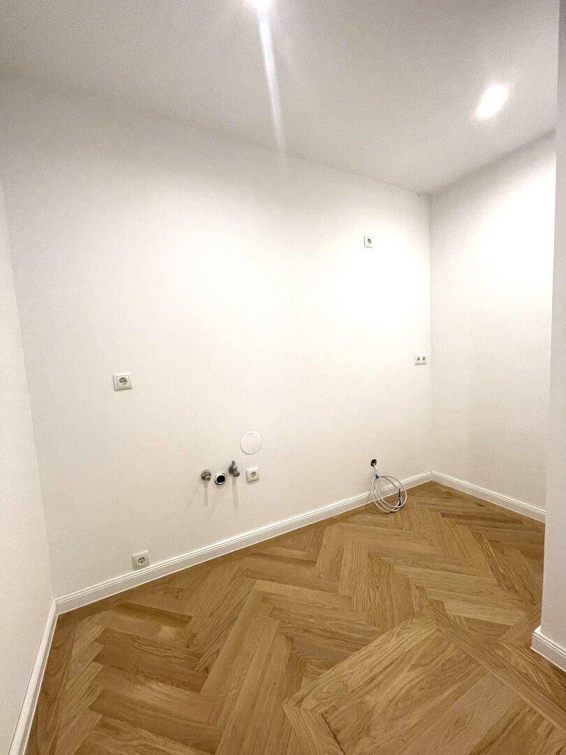 Kleiner Raum mit Fischgrätparkett und Anschlüssen für Waschmaschine oder Spüle.