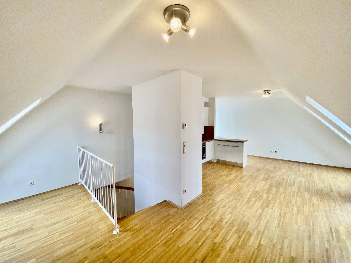 Heller Wohnbereich im Dachgeschoss mit Holzboden, Dachschrägen und offener Raumgestaltung, bereit zur Einrichtung.