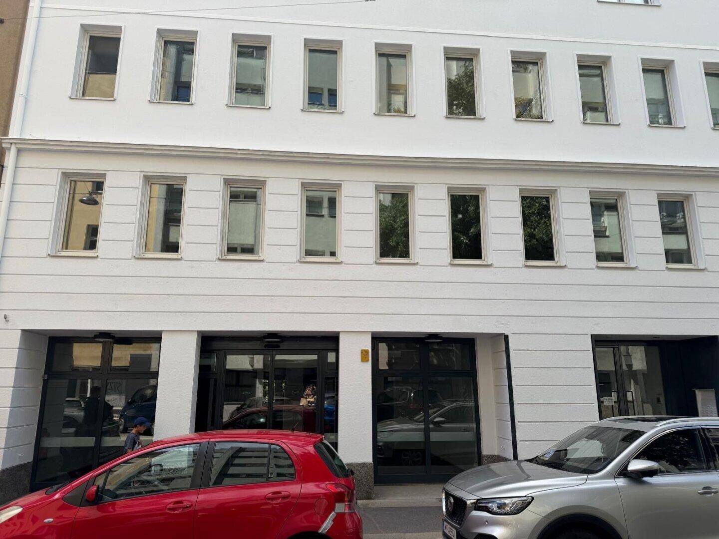 Frontansicht eines modernen Gebäudes mit vielen Fenstern und weißer, sauberer Fassade.