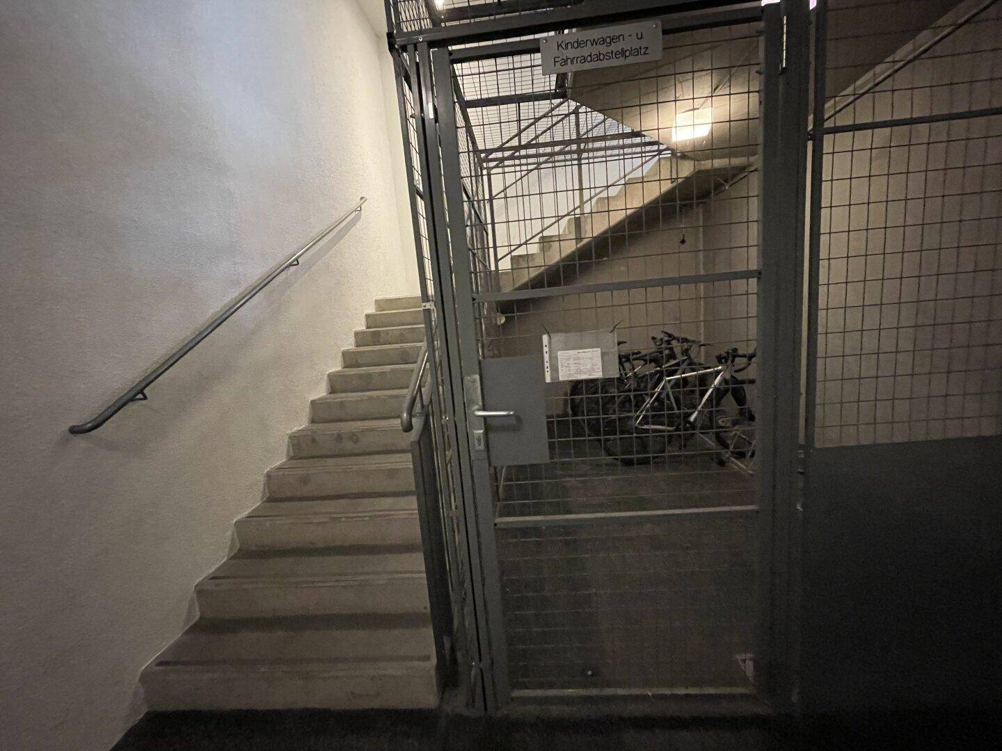 Treppenhaus mit einem gesicherten Bereich für Kinderwagen und Fahrräder im Untergeschoss des Gebäudes.