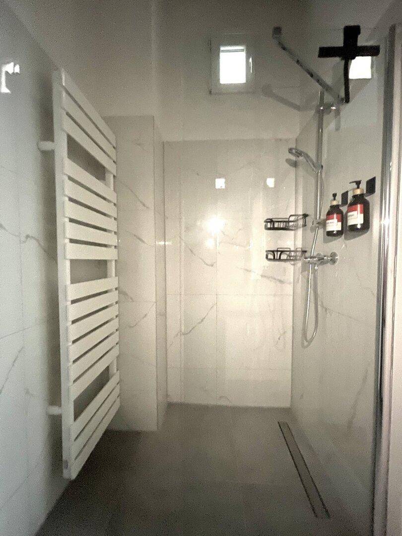 Elegantes Badezimmer mit ebenerdiger Dusche und beheiztem Handtuchhalter, in modernen Fliesen.
