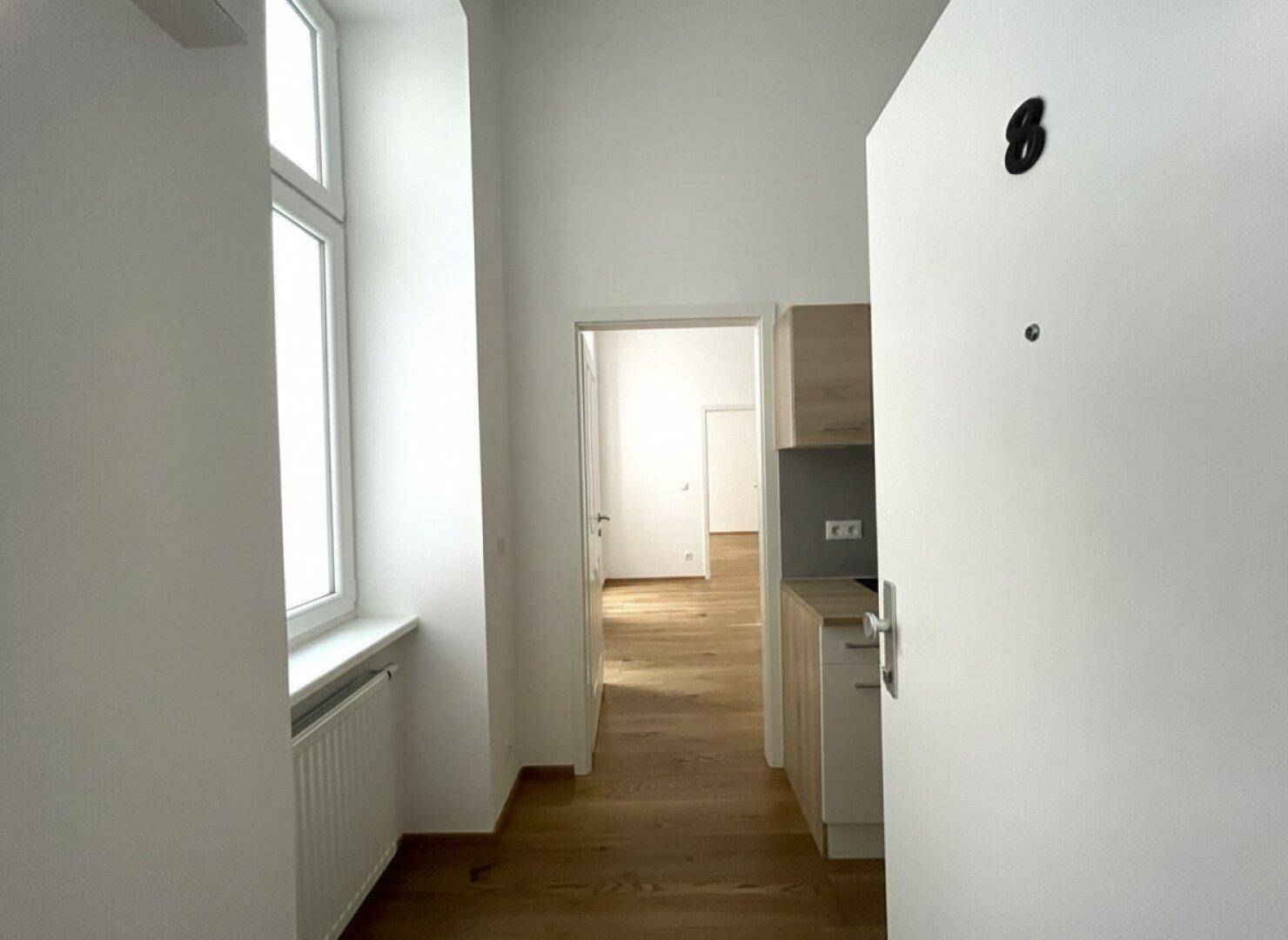 Eingangsbereich mit Blick auf eine moderne Küchenzeile und helle Fenster, die den Raum erhellen.