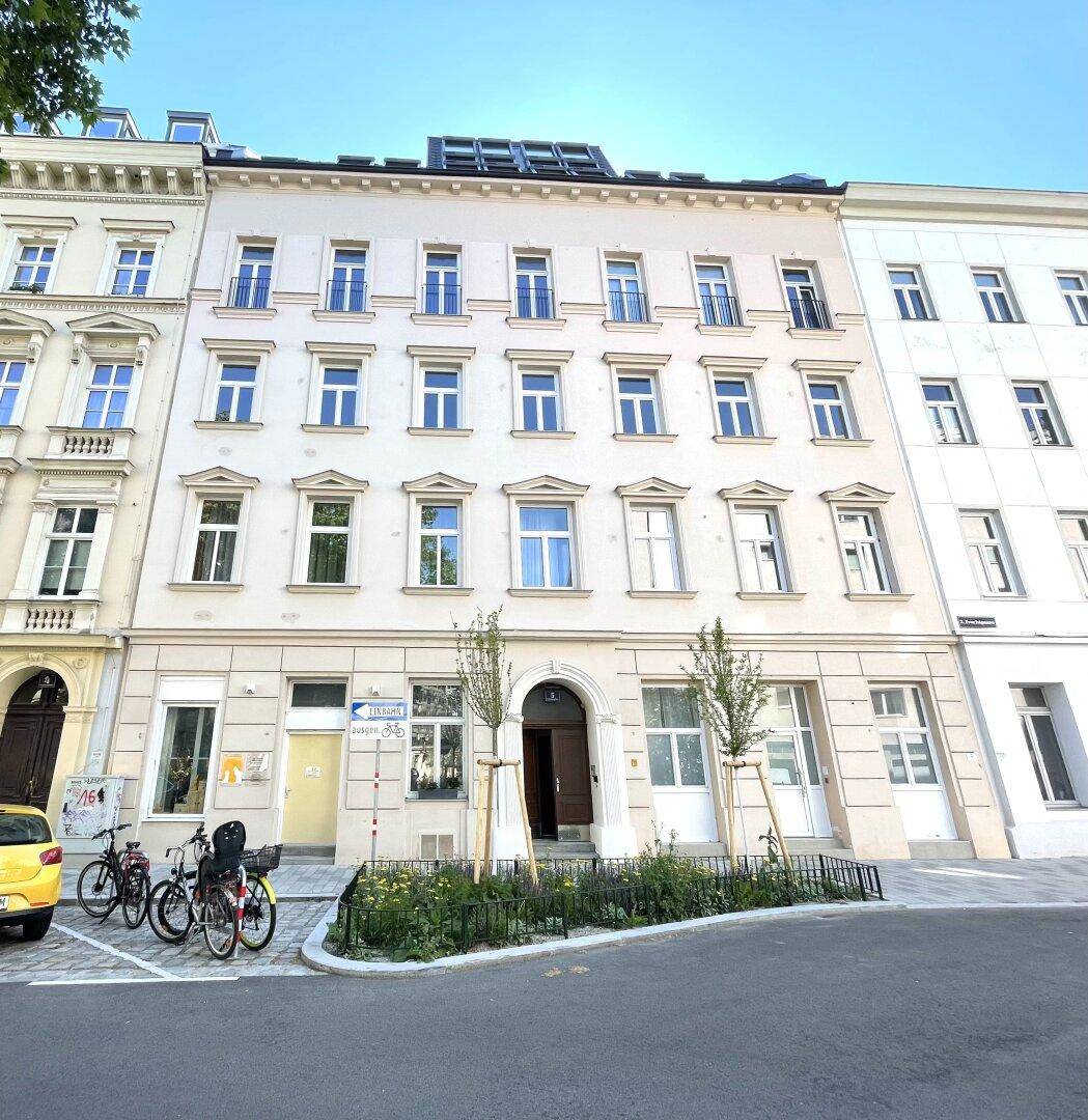 Klassische Fassade eines Wohnhauses mit vielen Fenstern und Solarpaneelen auf dem Dach.