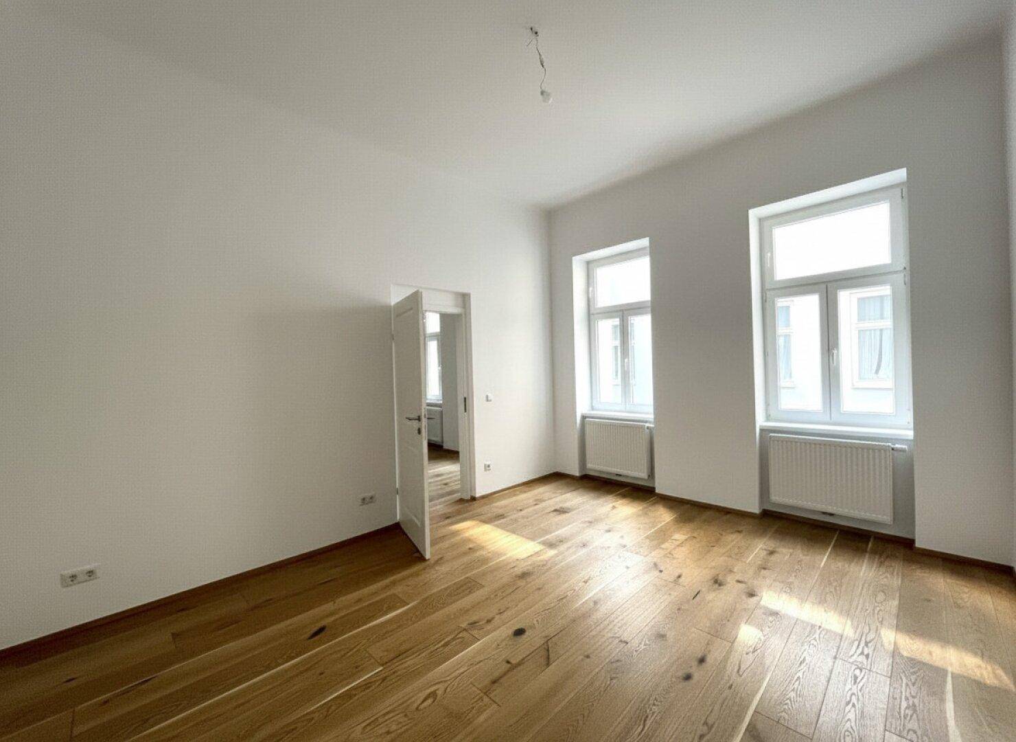 Geräumiges Zimmer mit Holzboden und zwei Fenstern, bietet vielseitige Nutzungsmöglichkeiten.