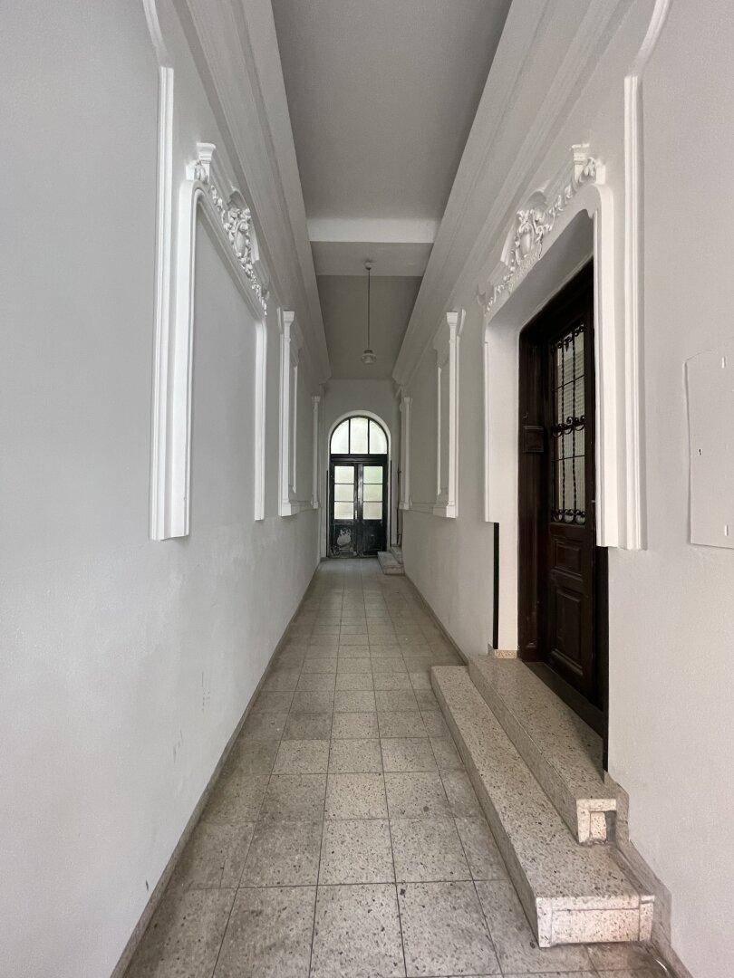 Langer, eleganter Flur mit Stuckverzierungen an Decke und Wänden sowie einem gefliesten Boden.