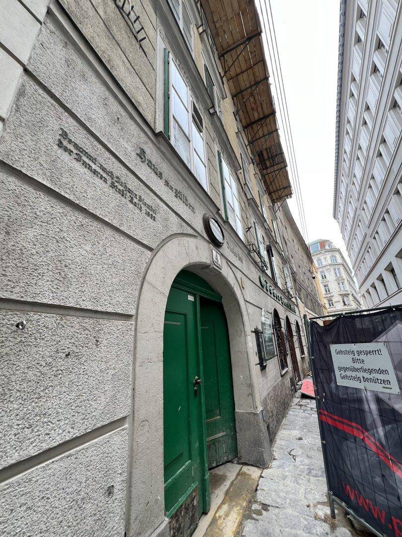 Historischer Eingang eines Gebäudes mit einer markanten grünen Holztür und Steinmauerwerk.