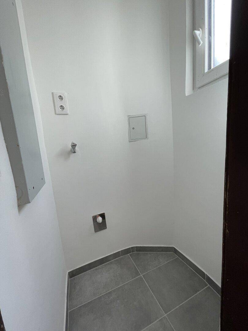 Kleiner Hauswirtschaftsraum mit Fliesenboden und Anschlüssen für Geräte.