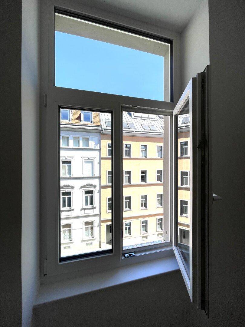 Geöffnetes Fenster mit Blick auf die Fassaden der gegenüberliegenden Gebäude.
