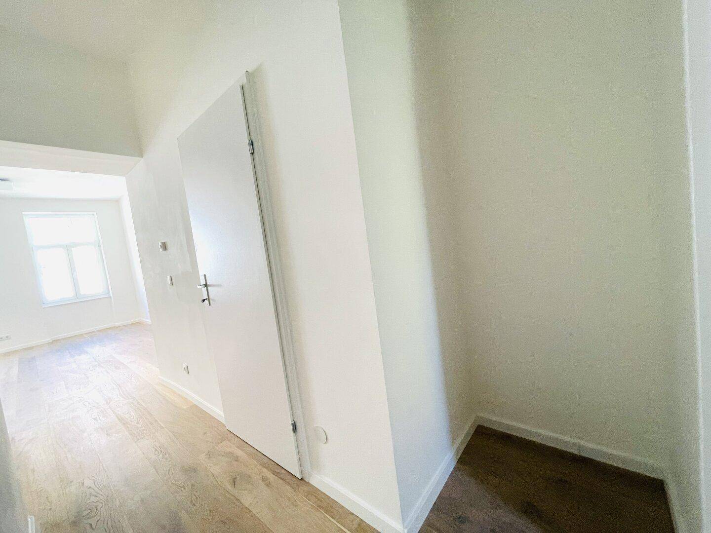 Heller Flur mit Parkettboden und einer kleinen Nische, ideal als Abstellraum.