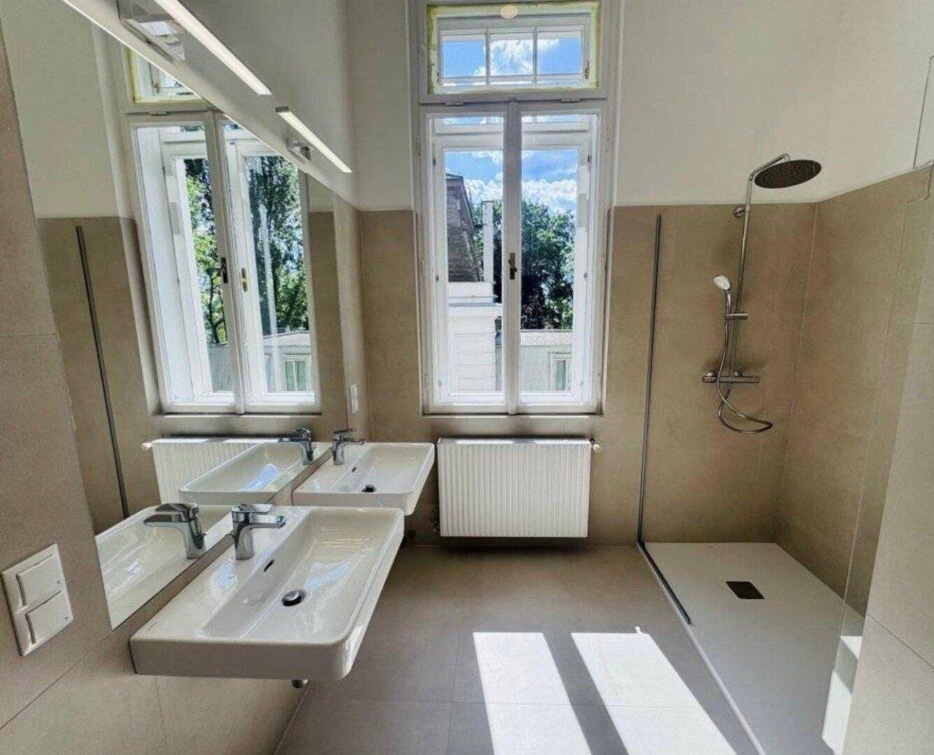 Modernes Badezimmer mit Doppelwaschbecken, ebenerdiger Dusche und großem Fenster.