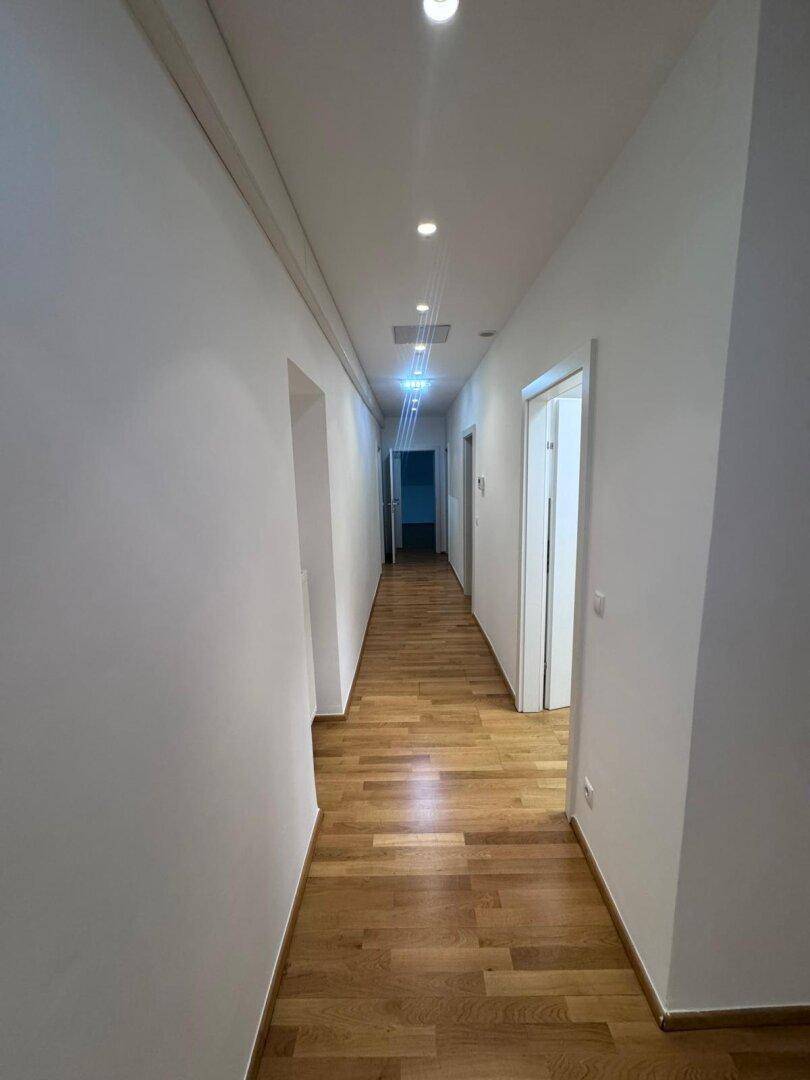 Langer, heller Flur mit Holzparkett und Einbaustrahlern, der zu weiteren Räumen führt.