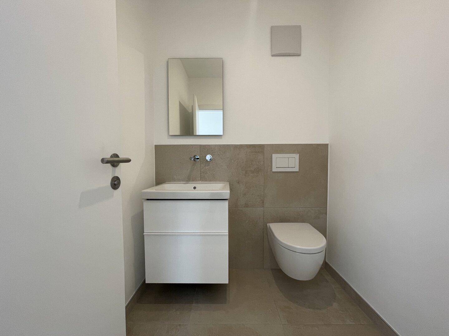 Modernes Gäste-WC mit wandhängender Toilette und kleinem Waschbecken.