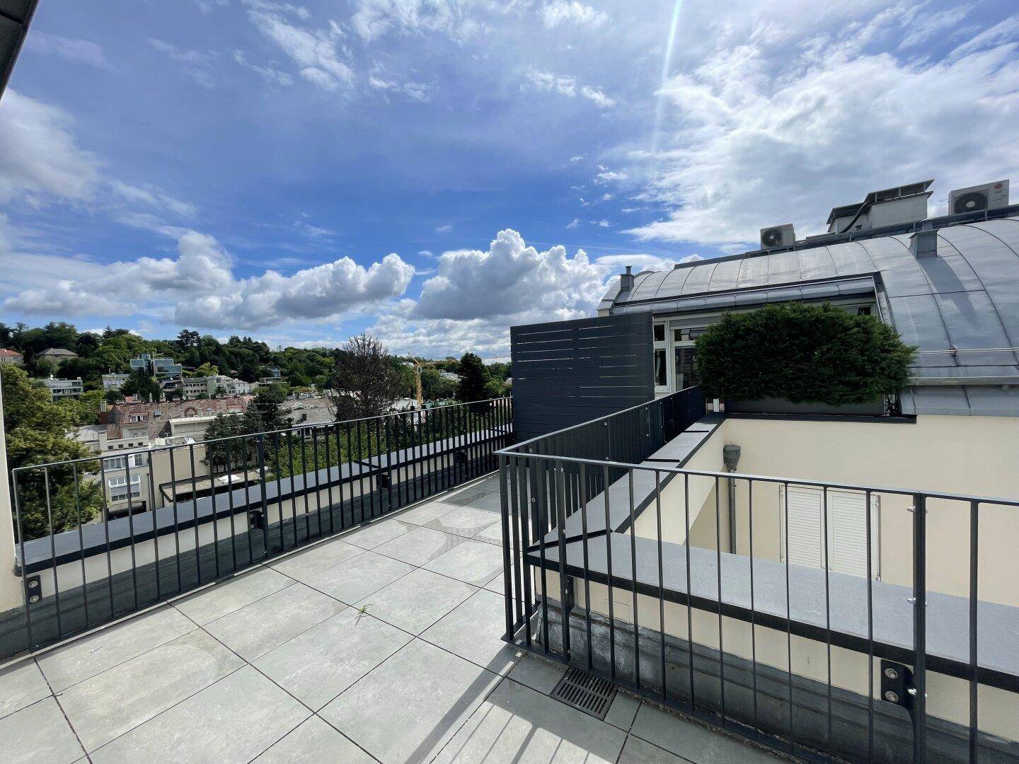Sonniger Dachterrassenbereich mit Fliesenboden und Panoramablick auf die umliegende Landschaft.