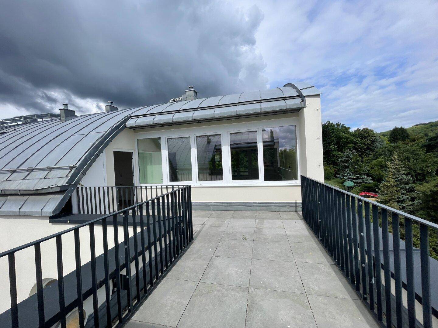 Geräumige Dachterrasse mit Fliesenboden und weitem Blick über die grüne Umgebung.