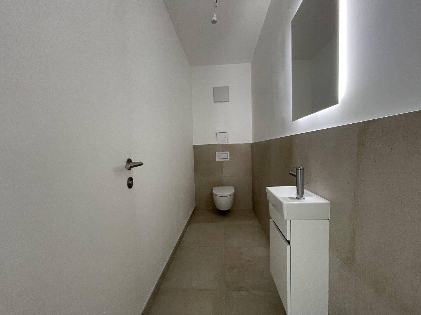 Modernes Gäste-WC mit wandhängender Toilette und kleinem Waschbecken.
