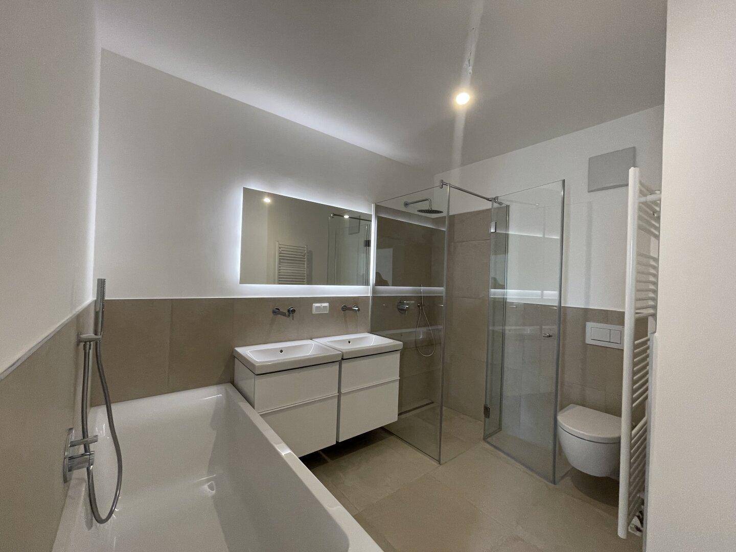 Modernes Badezimmer mit Badewanne, Doppelwaschbecken, begehbarer Dusche und beheiztem Handtuchhalter.