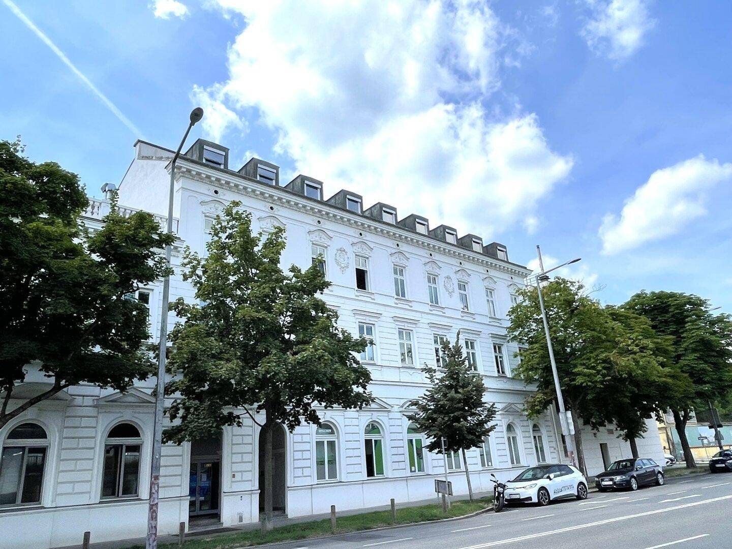 Historisches Gebäude mit vielen Fenstern und Dachgauben unter einem bewölkten Himmel.