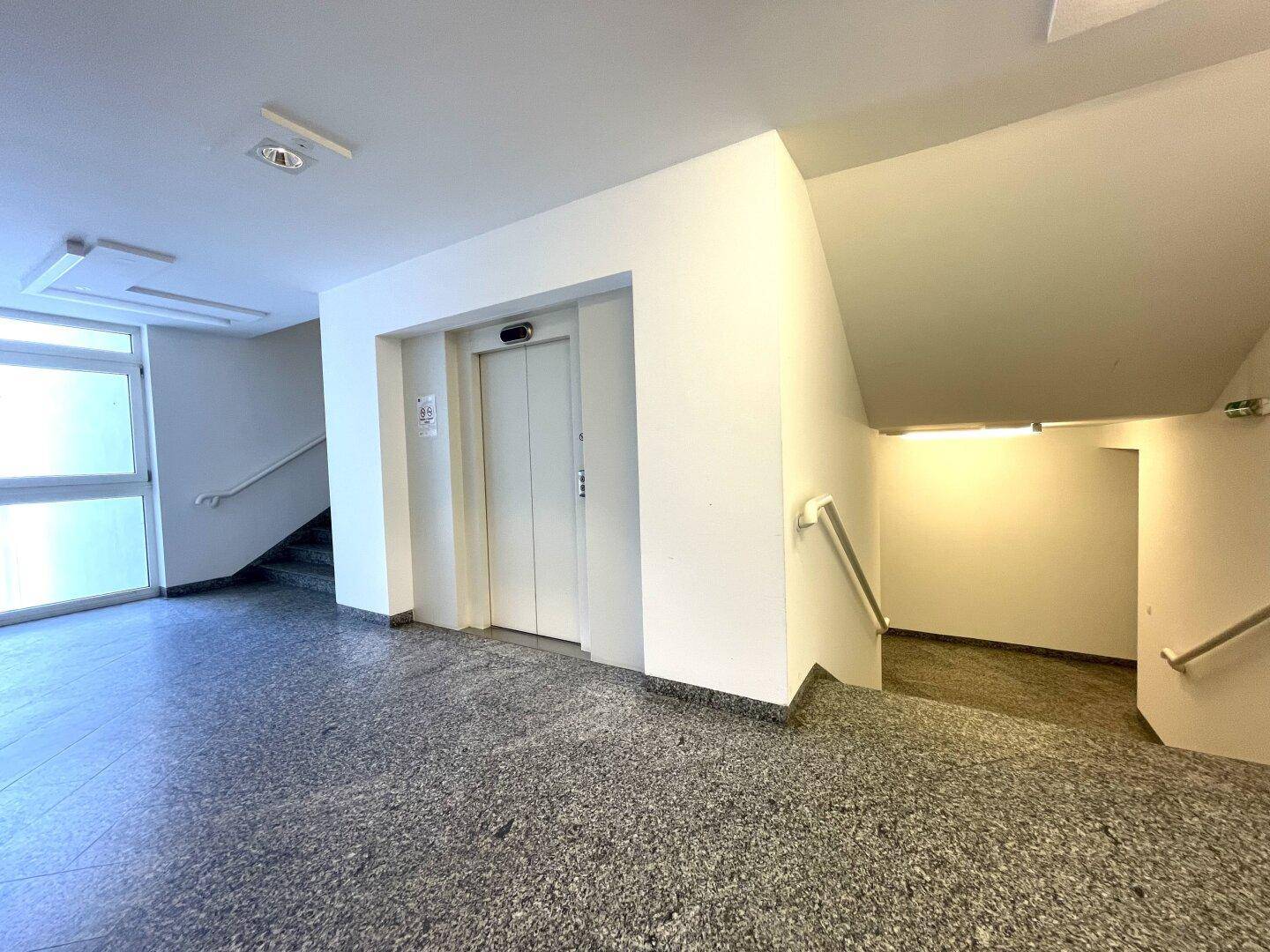 Eingangsbereich mit Aufzug und Treppenhaus, ausgestattet mit Granitboden.