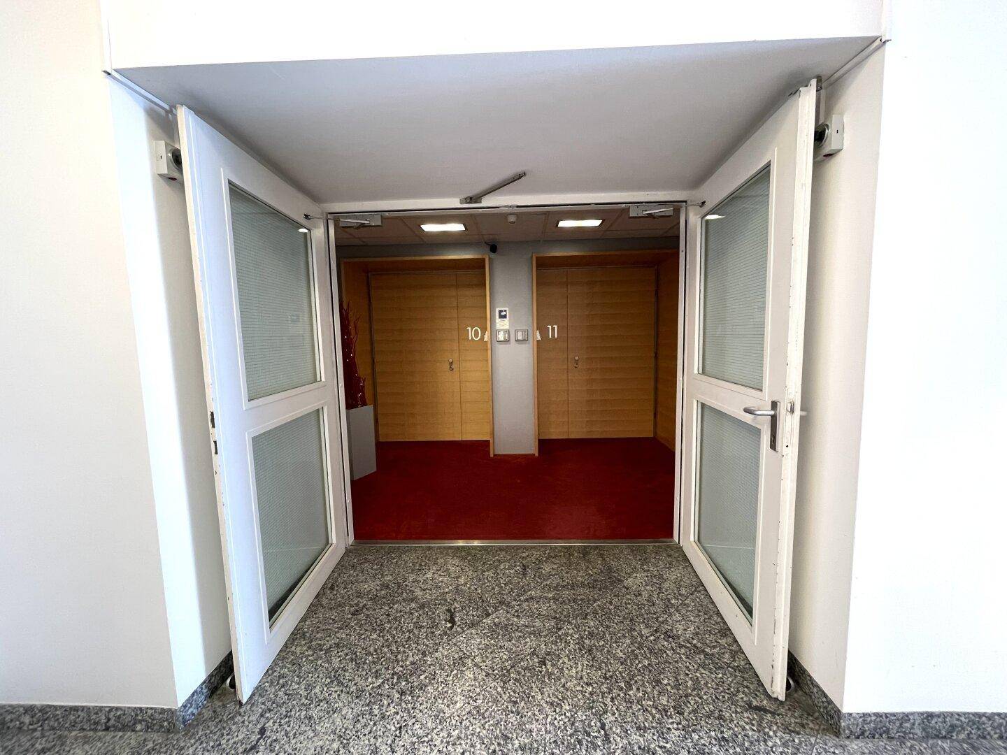 Eingangsbereich mit Doppeltüren und Teppichboden, der zu den Büroeinheiten führt.