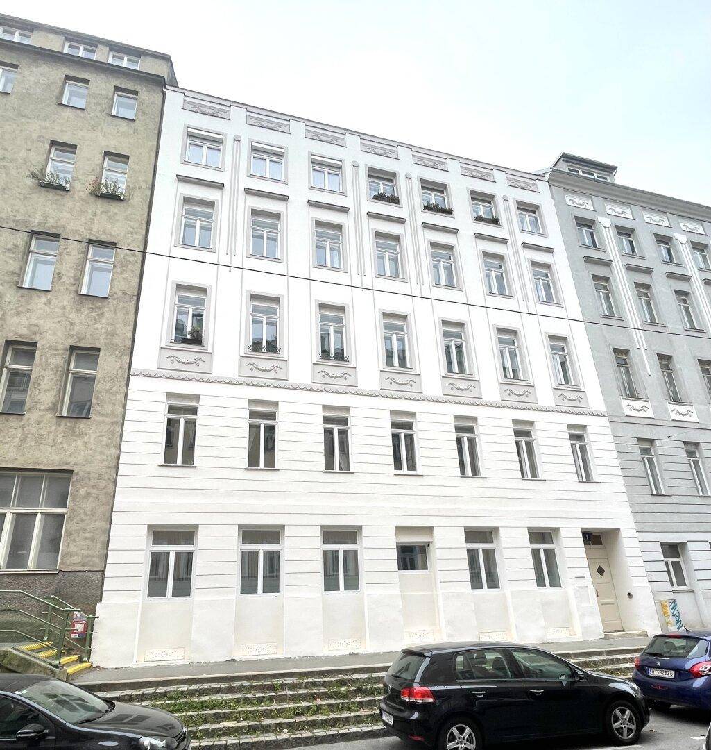 Renovierte Fassade eines Altbaus mit vielen Fenstern und klassischer Architektur.