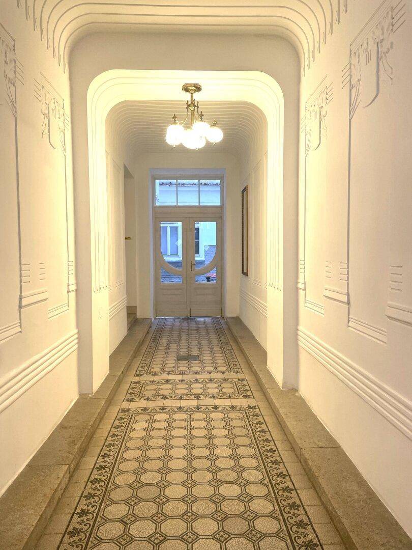 Eleganter Eingangsbereich mit gemusterten Fliesen, hohen Decken und klassischer Beleuchtung.