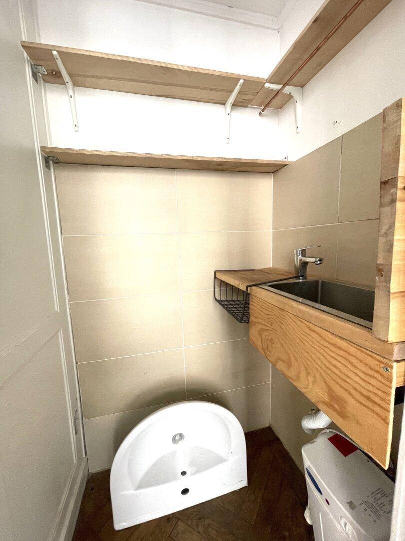 Kleiner Raum mit Fliesenwänden, einem Waschbecken und Regalen, möglicherweise ein Hauswirtschaftsraum.