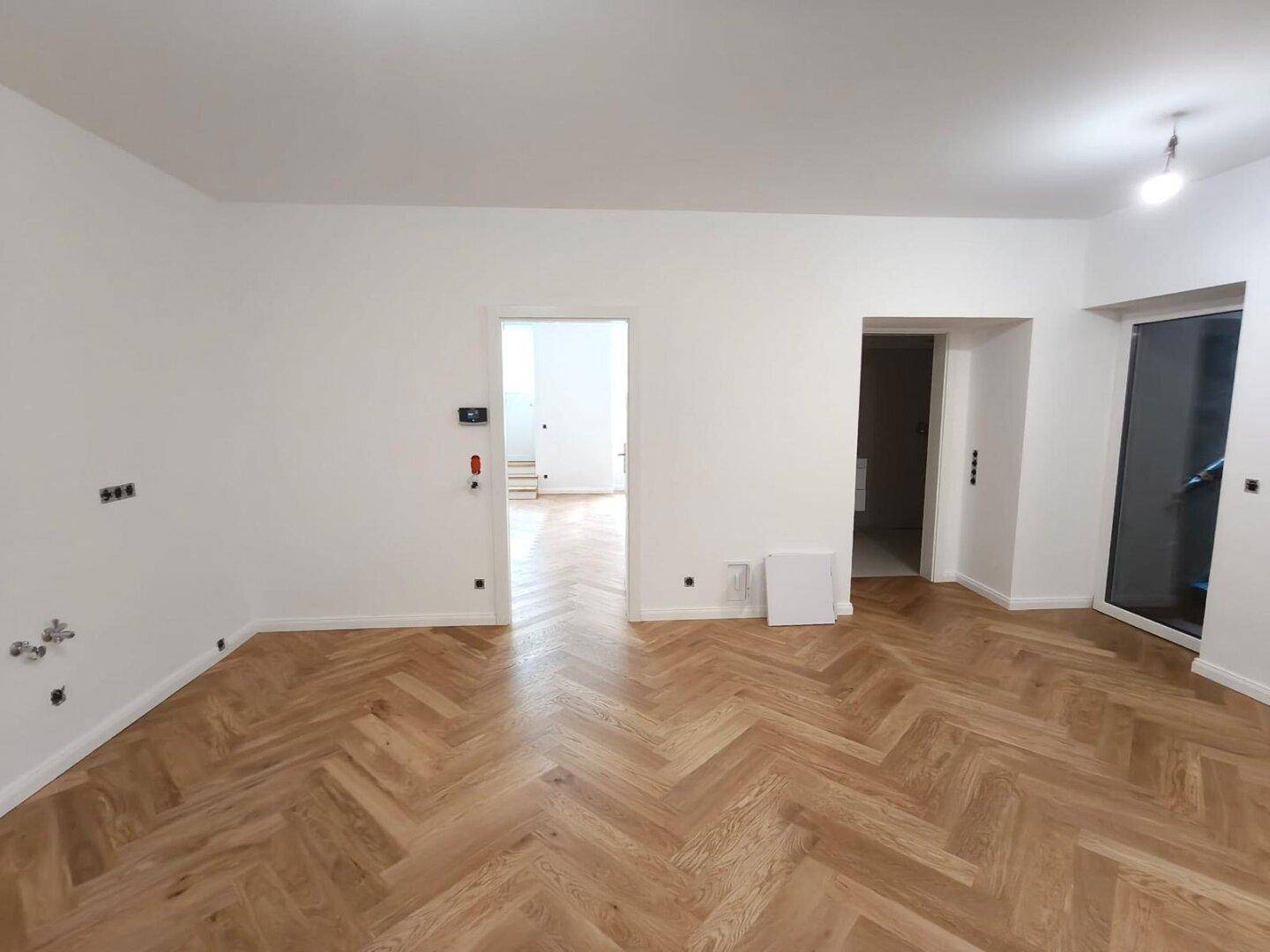Geräumiges, helles Zimmer mit Fischgrätparkett und mehreren Türen, bietet flexible Nutzungsmöglichkeiten.
