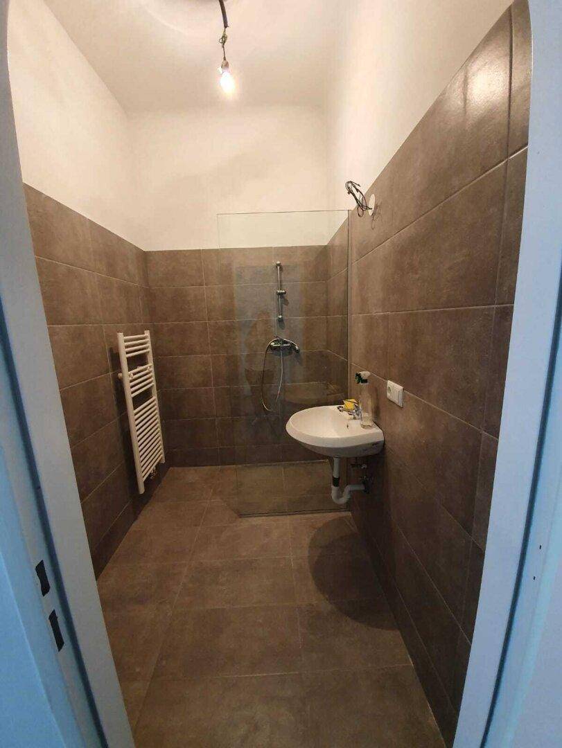 Modernes Badezimmer mit braunen Fliesen, begehbarer Dusche und beheiztem Handtuchhalter.