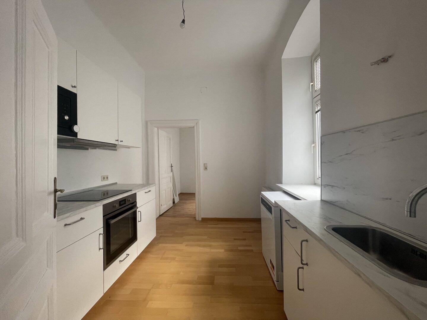 Moderne Einbauküche mit weißen Schränken, Marmorarbeitsplatte und integrierten Geräten für Komfort.