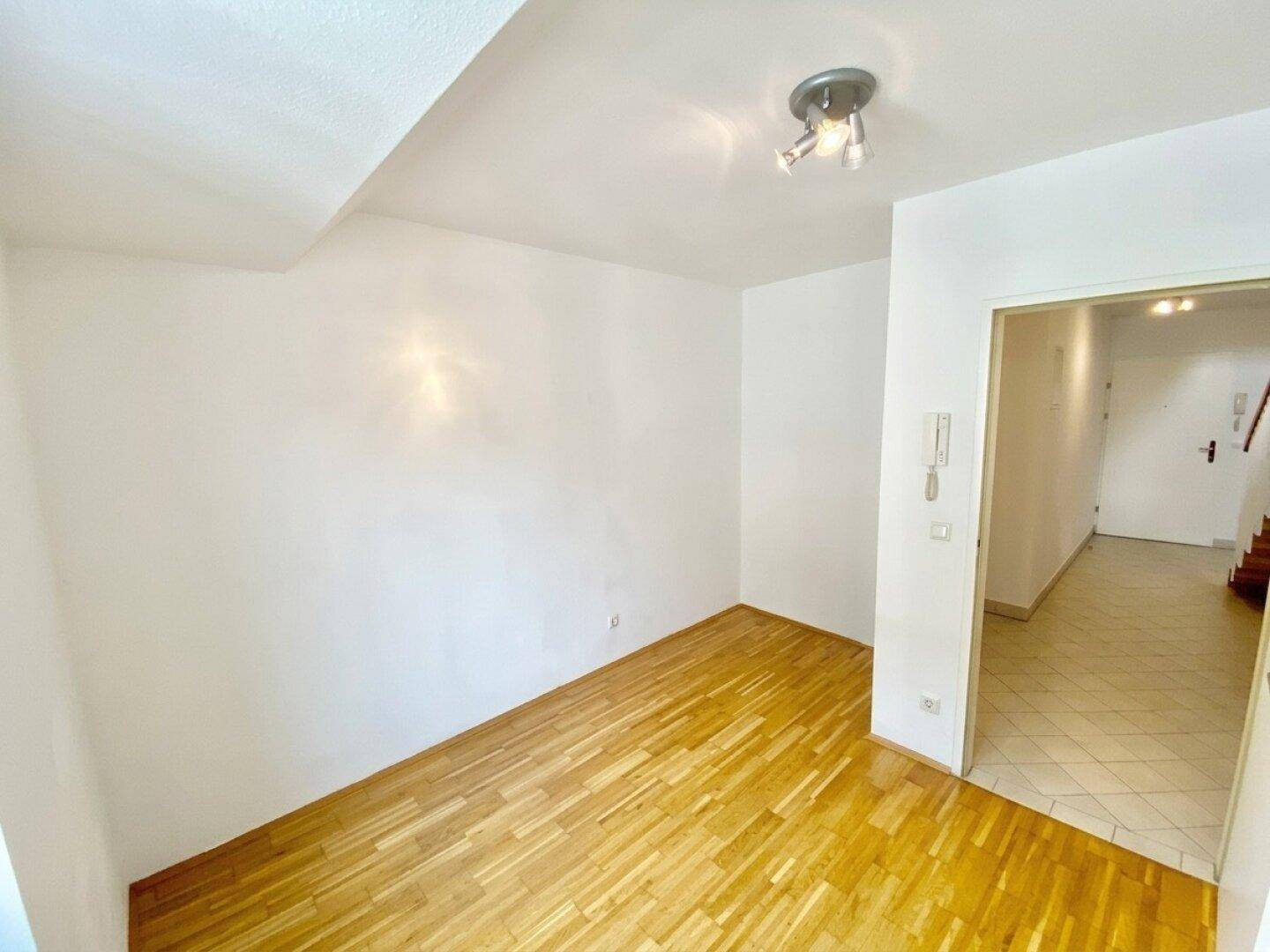 Heller Eingangsbereich mit Holzboden und Zugang zu weiteren Räumen, funktional und einladend gestaltet.