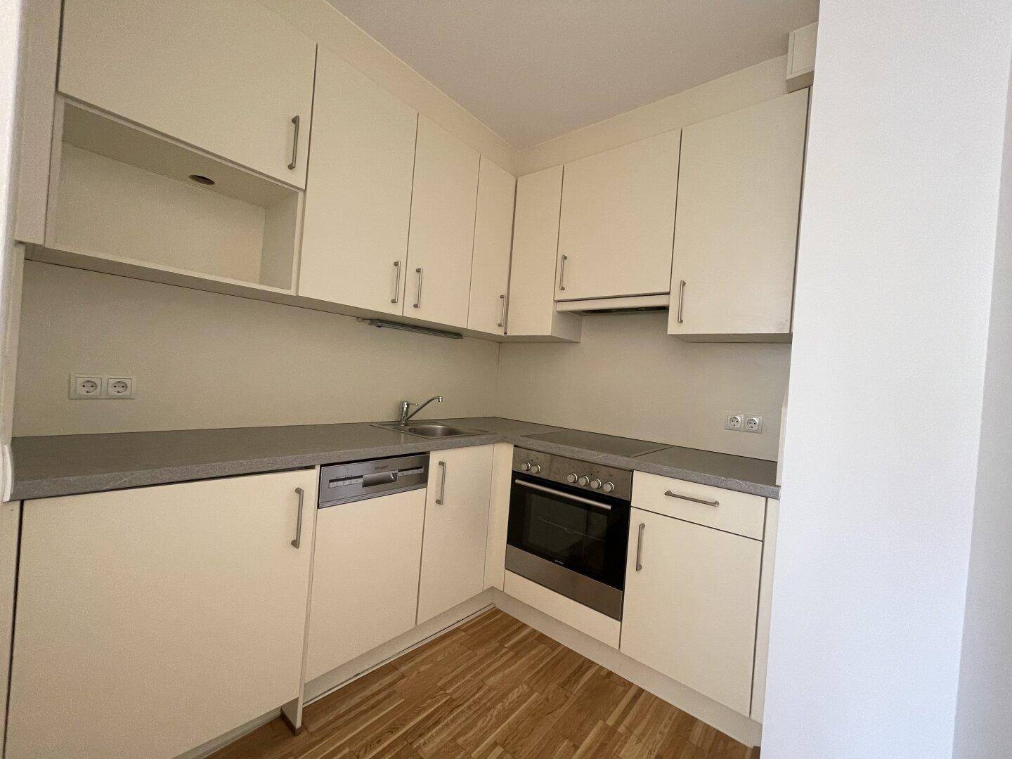 Funktionale Küche mit hellen Einbauschränken, Spülmaschine und integriertem Backofen.