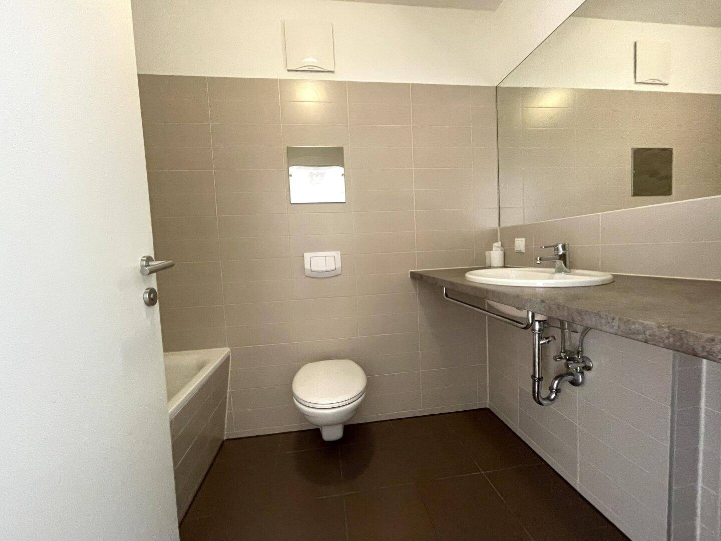 Modernes Badezimmer mit wandhängendem WC, Waschbecken und großem Spiegel.