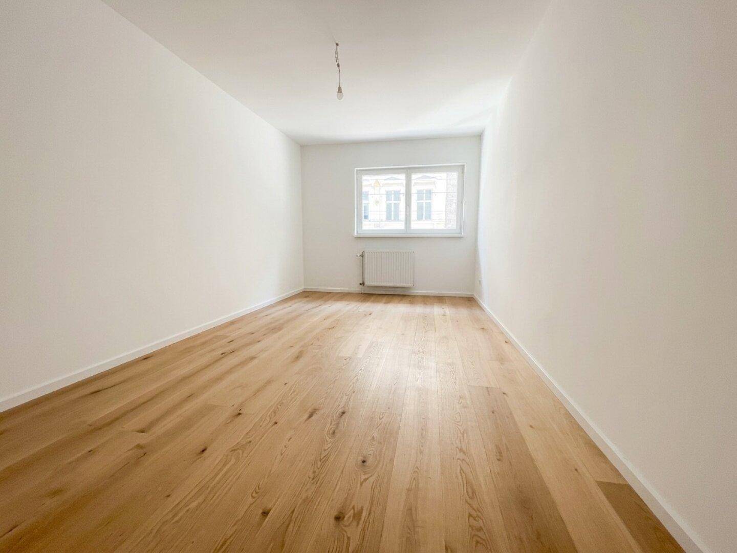 Helles Schlafzimmer mit neuem Holzfußboden und Blick auf die Stadt.