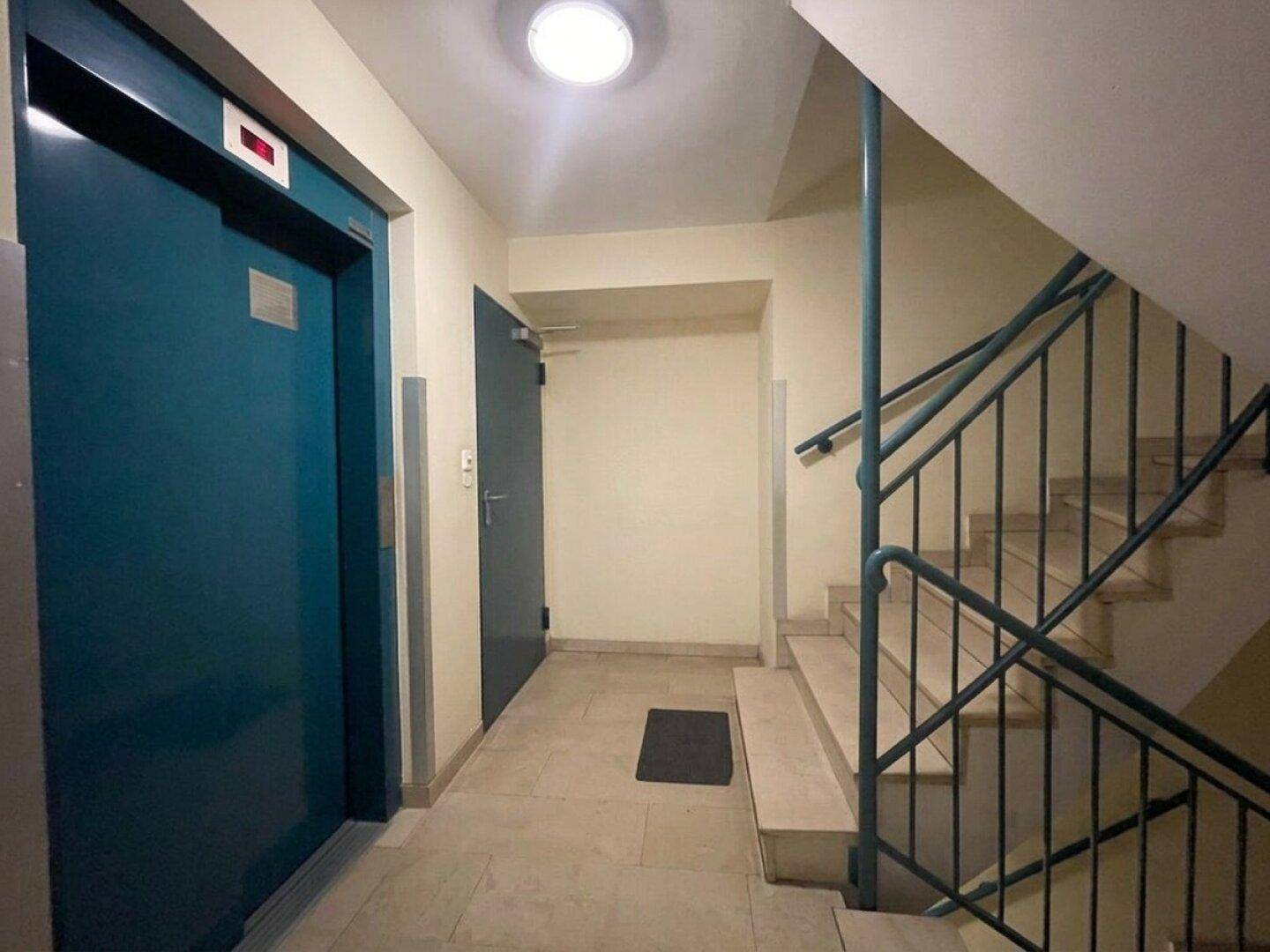 Heller Treppenaufgang und Flur mit Aufzug in einem Mehrfamilienhaus.