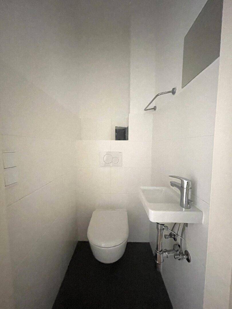 Kleines Gäste-WC mit modernen Fliesen, wandhängendem WC und einem kompakten Waschbecken.