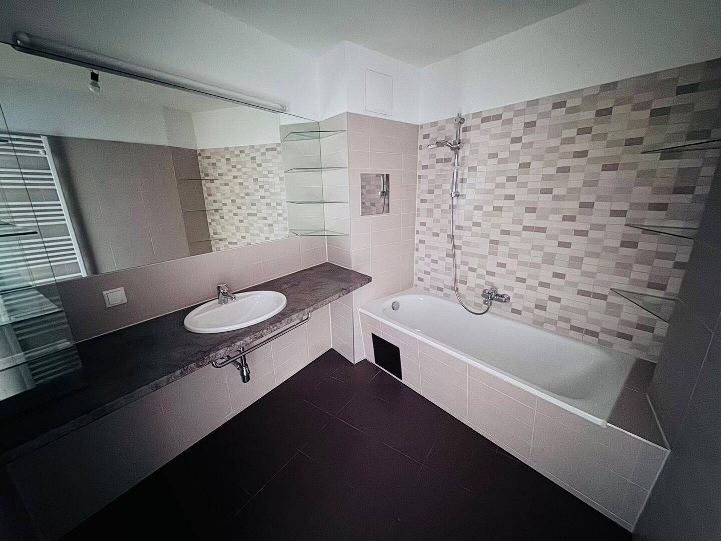 Modernes Badezimmer mit Badewanne, Einzelwaschbecken und Wandfliesen in neutralen Tönen.