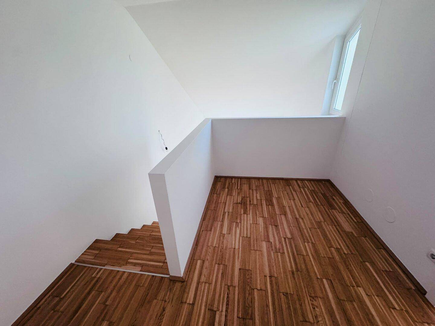 Heller Treppenaufgang mit Holzparkett, der verschiedene Ebenen der Wohnung verbindet.
