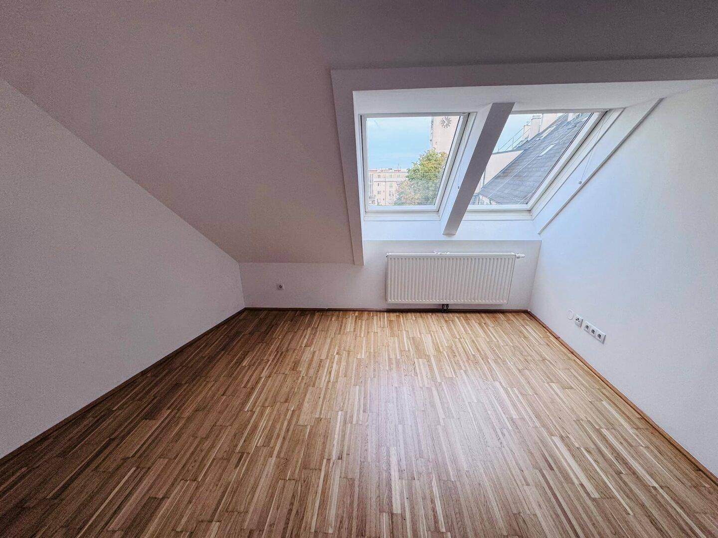 Helles Zimmer mit Parkettboden und großem Dachfenster, ideal als Schlaf- oder Arbeitszimmer.
