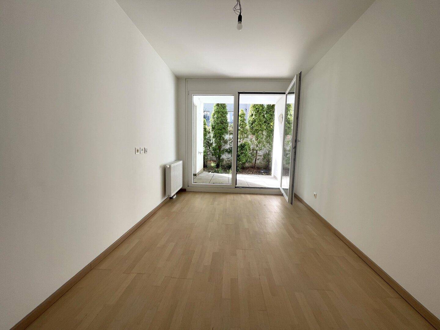 Lichtdurchfluteter Raum mit Parkettboden und direktem Zugang zur Terrasse oder zum Gartenbereich.