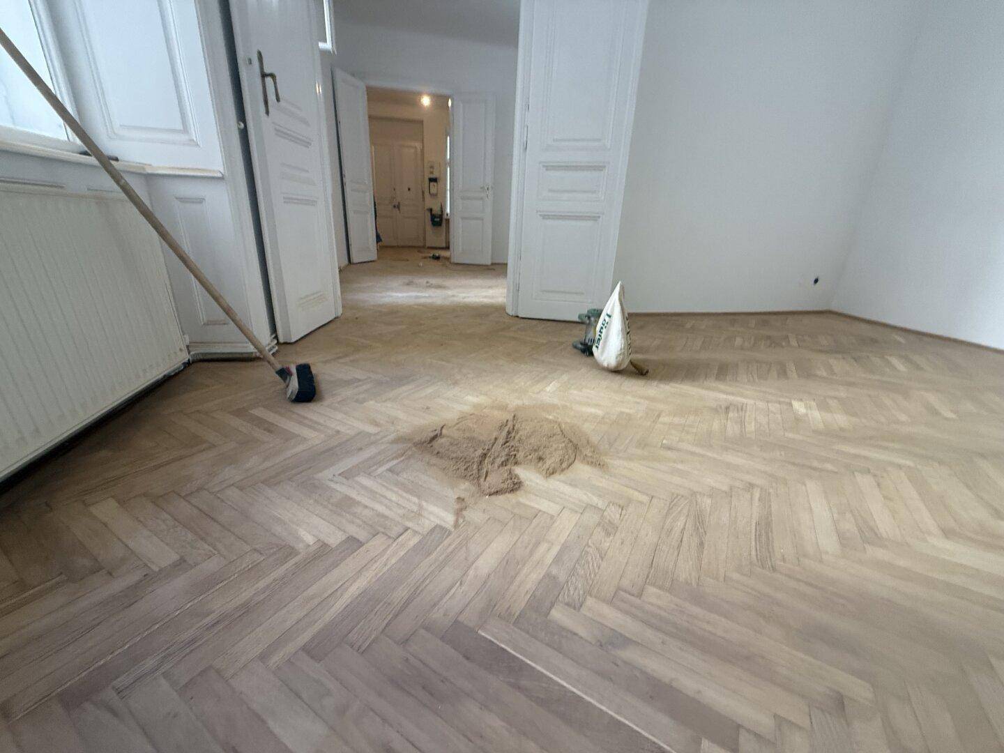Innenraum mit Fischgrätparkettboden, der auf eine Renovierung hindeutet.