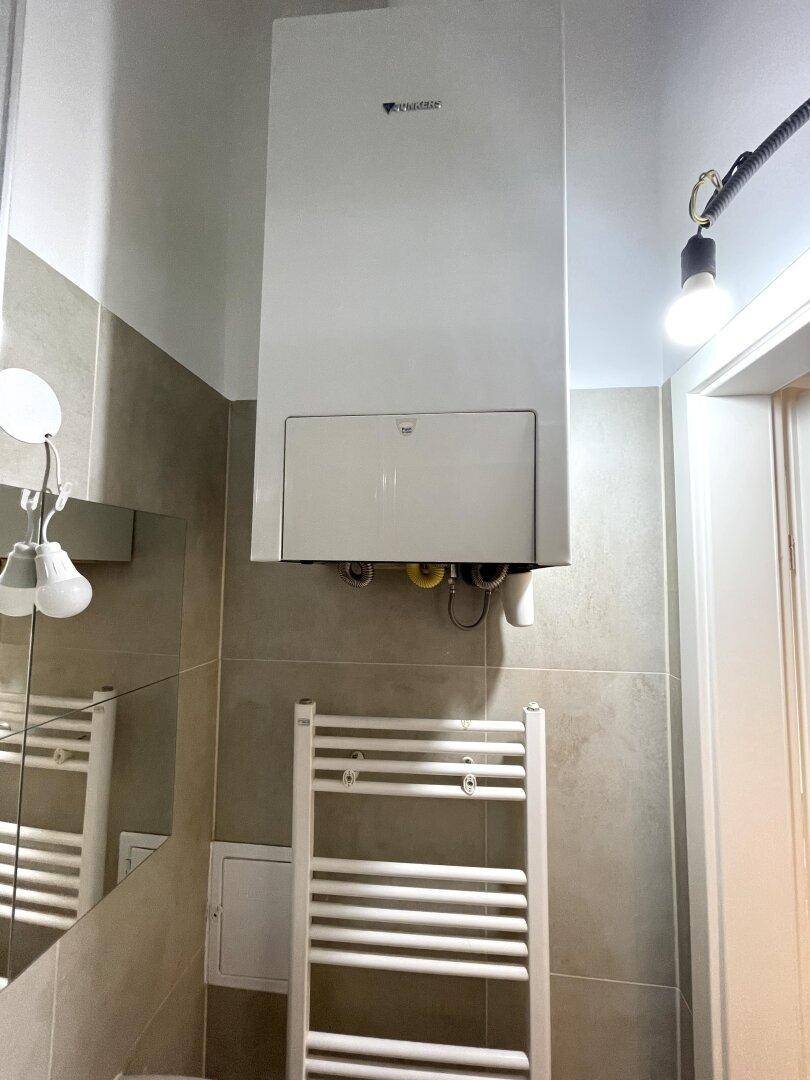Modern gefliestes Badezimmer mit wandmontiertem Heizkessel und beheiztem Handtuchhalter.
