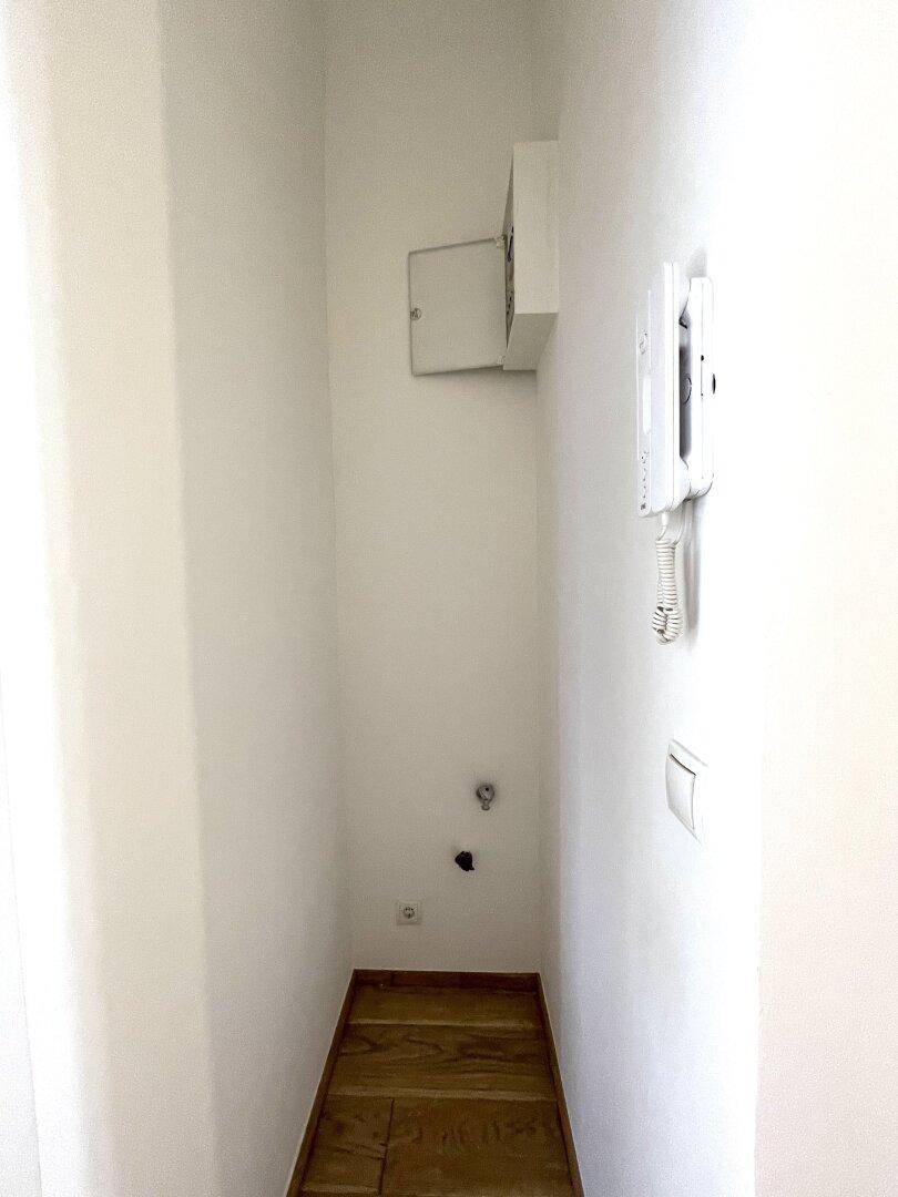 Kleiner Nischenbereich im Flur mit Gegensprechanlage und Anschlüssen, ideal für eine Waschmaschine.
