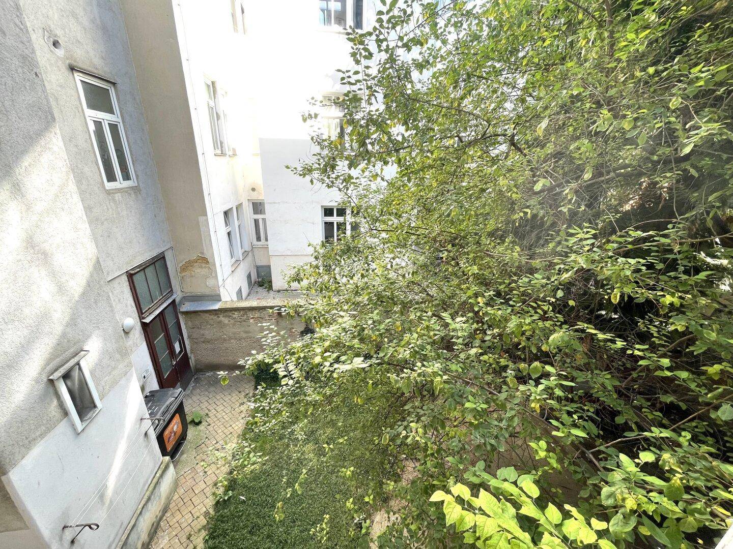 Blick auf einen begrünten Innenhof von oben, umgeben von Gebäuden.