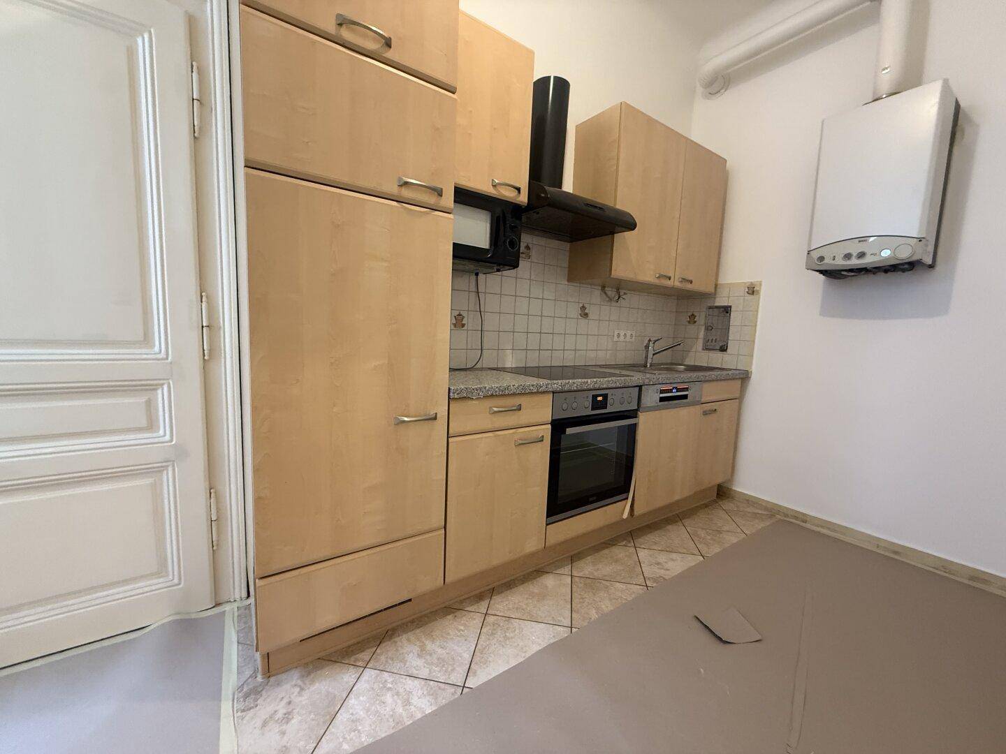 Funktionale Küche mit hellen Holzschränken, Einbaugeräten und Gastherme.
