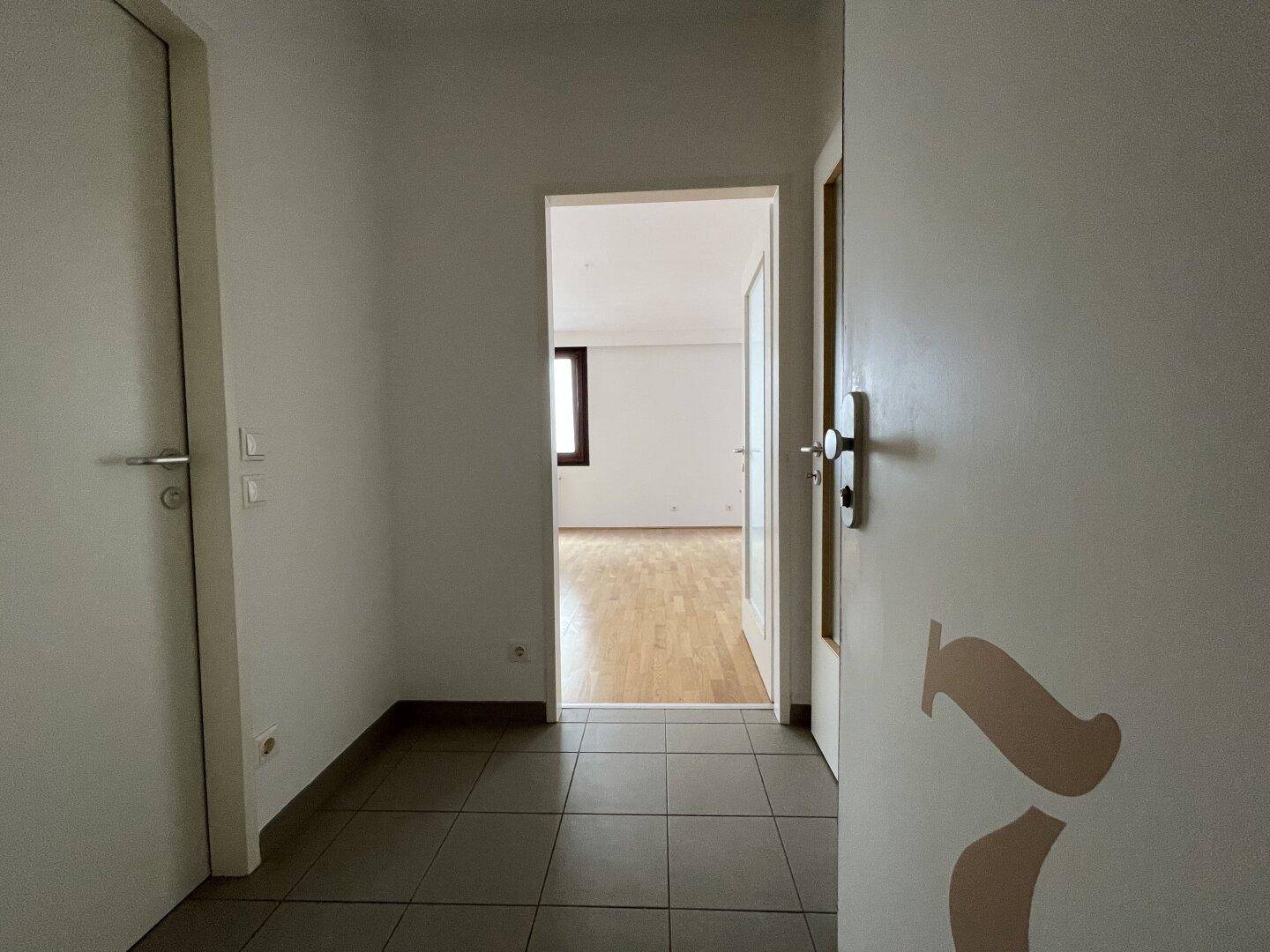 Heller Flur mit Fliesenboden, der den Blick in ein weiteres Zimmer freigibt.