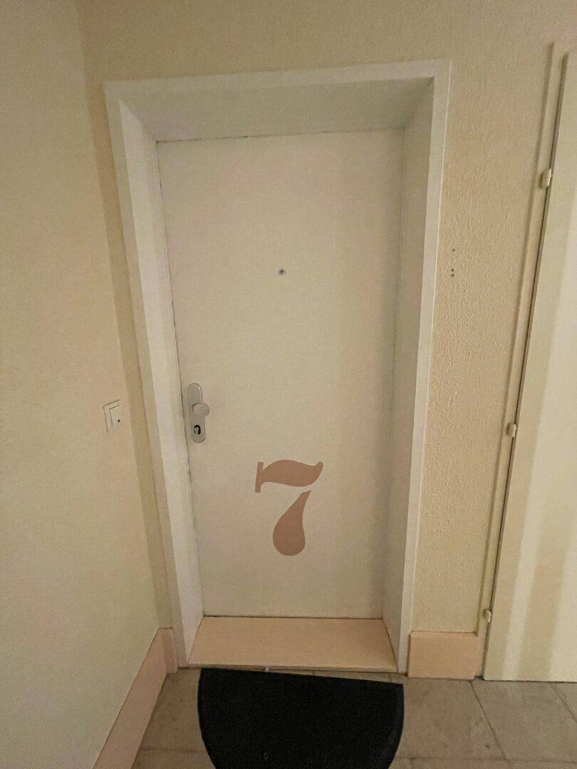 Eingangstür einer Wohnung mit der Nummer Sieben in einem Mehrfamilienhaus.