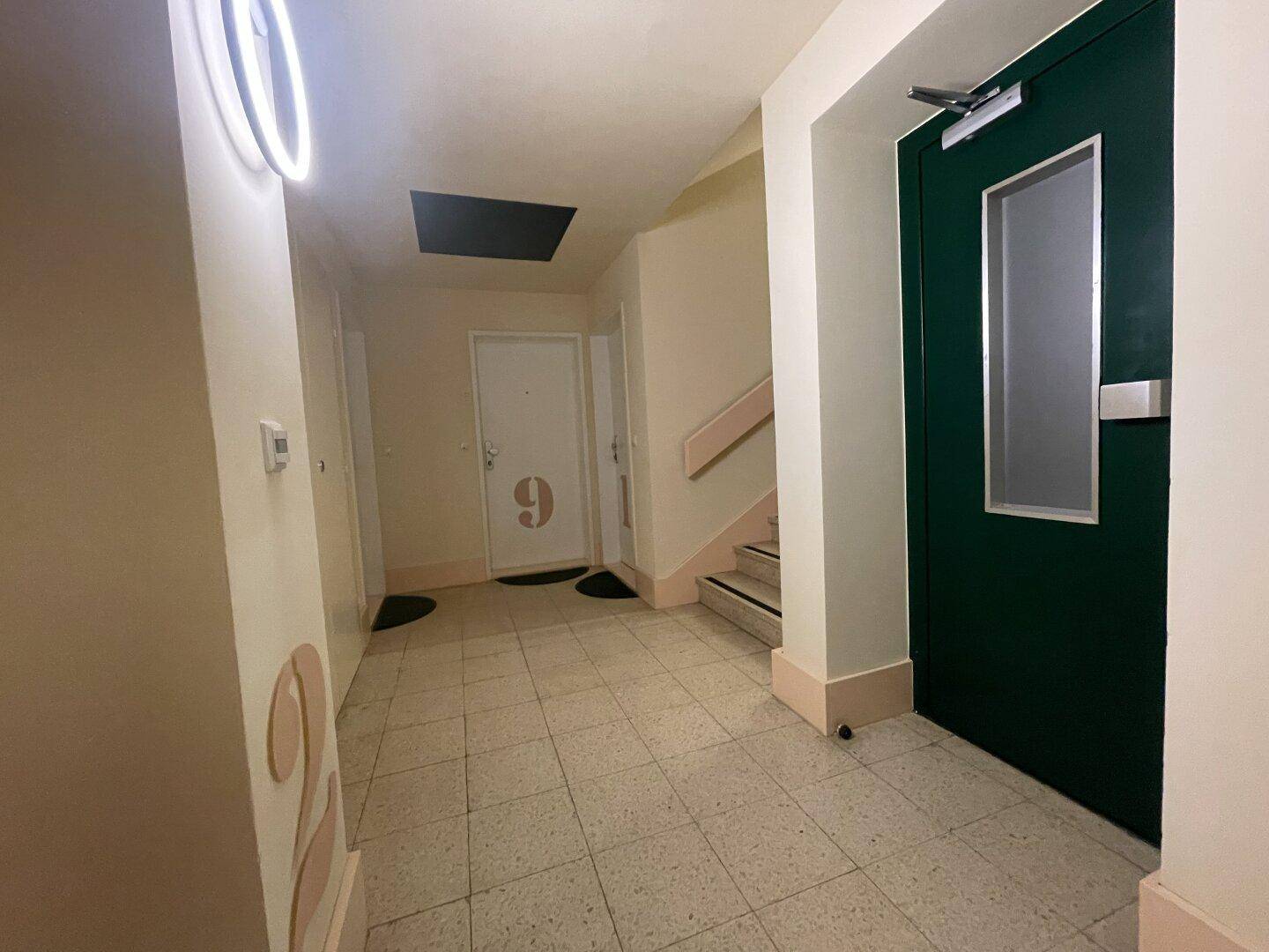 Treppenhaus und Flur eines Mehrfamilienhauses mit Zugang zu den Wohnungen und einem Aufzug.